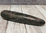 Natural black and pink gemstone wand on wood grain background