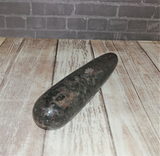 Rhodonite wand on wood grain background