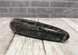 Natural black and pink gemstone wand on wood grain background
