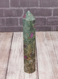Ruby Fushite carved wand obelisk on brick and wood grain background