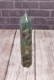 Ruby Fushite carved wand obelisk on wood grain background