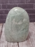 Hand carved green gemstone tower on brick and wood grain background
