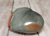 Side view of jasper heart on wood grain background