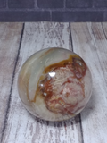 Polychrome Jasper Sphere from Madagascar GGandJ.com on wood grain background Gypsy Gems & Jewelry Naturally Unique