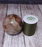 Polychrome Jasper Sphere from Madagascar GGandJ.com on wood grain background with thread spool size reference Gypsy Gems & Jewelry Naturally Unique