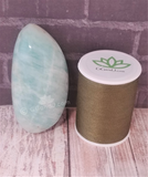Amazonite gallet from Madagascar on wood grain background with thread spool size reference