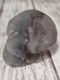 Striped fluorite Rainbow Carved Gemstone Skull GGandJ.com on Wood grain background