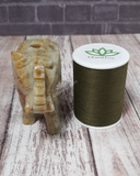 Carved Gemstone Elephant on Wood Grain background with thread spool size reference