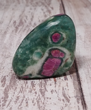 Ruby Fushite Tumbled gemstone on wood grain background green red white  gift idea