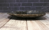 Side view of ammonite heart plate C on wood grain background