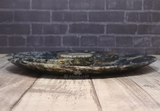 Side view of ammonite spiral plate on wood grain background