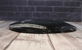 Side view of ammonite oval plate on wood grain background