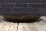 Side view of ammonite oval plate on wood grain background