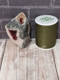 Wine colored Cobalto Calcite from Morocco on wood grain background with thread spool size reference