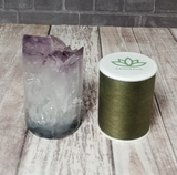 Amethyst tower next to thread spool on wood grain