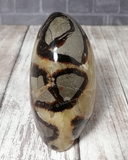 Brown gray and yellow carved gemstone on wood grain background