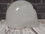 Side view of clear quartz skull on wood grain background